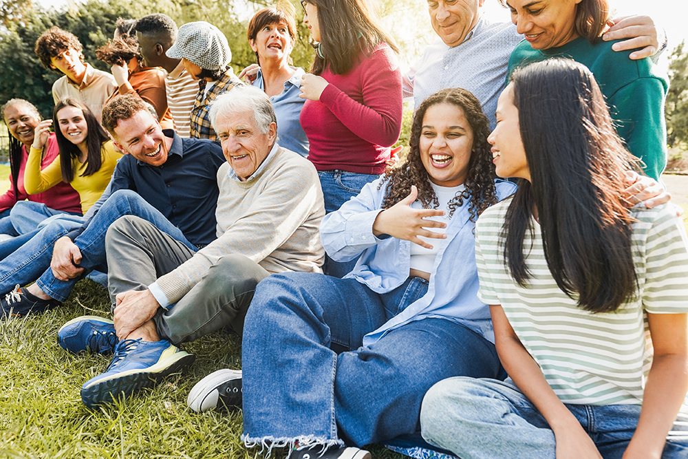 A multigenerational group sits on a lawn talking